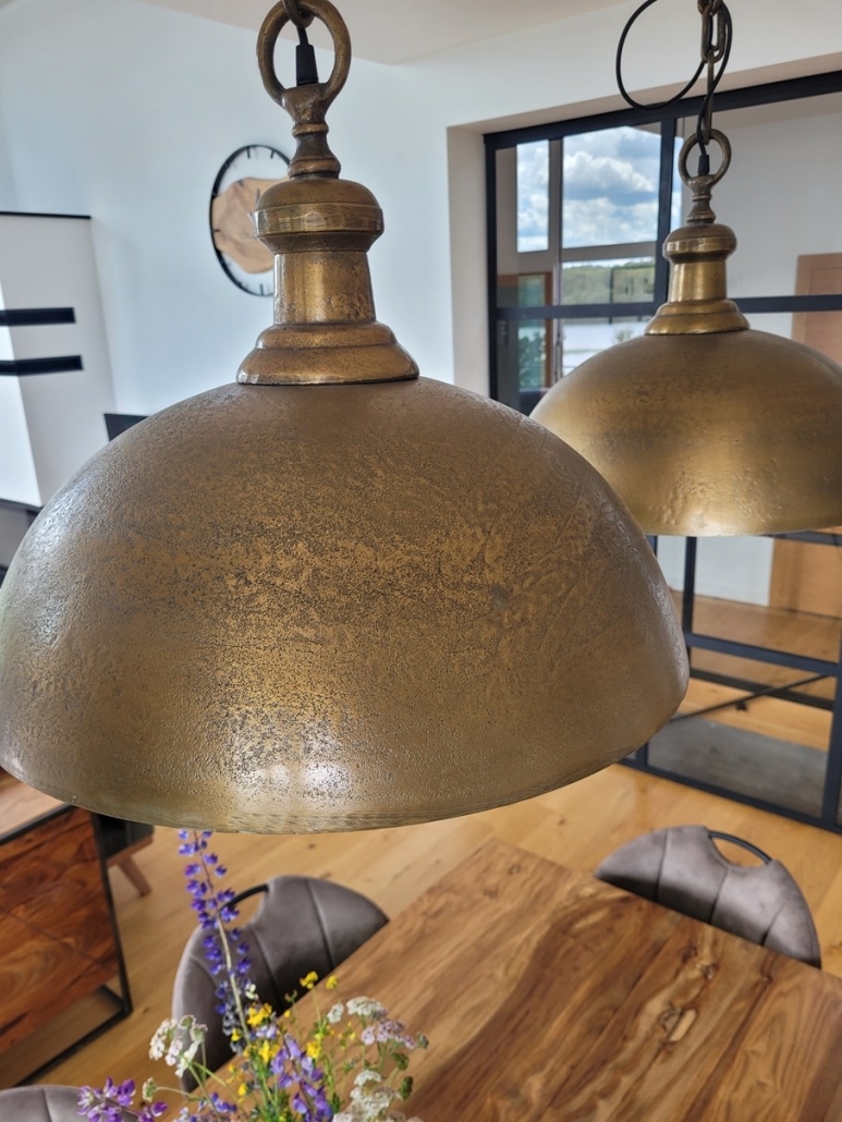 Duże lampy mosiężne w stylu industrialnym nad stołem w jadalni.